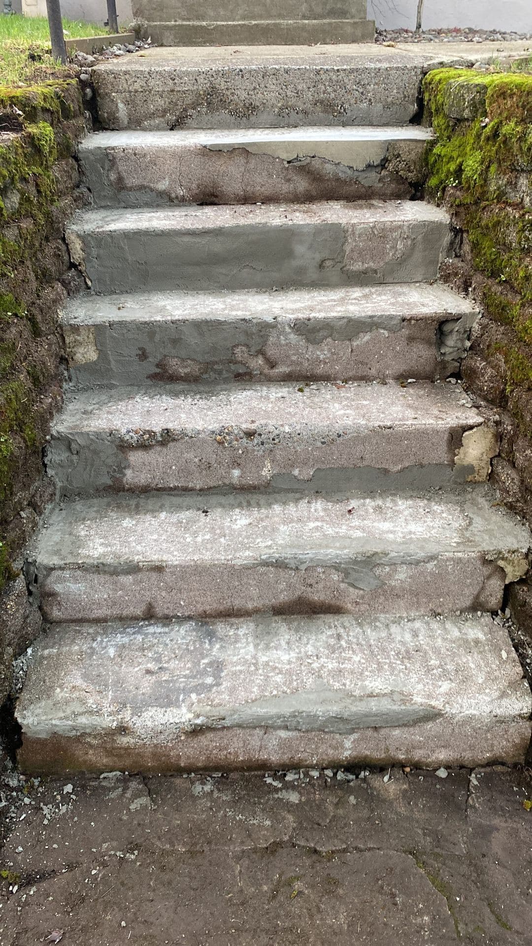 Patched concrete step treads between moss-covered retaining walls