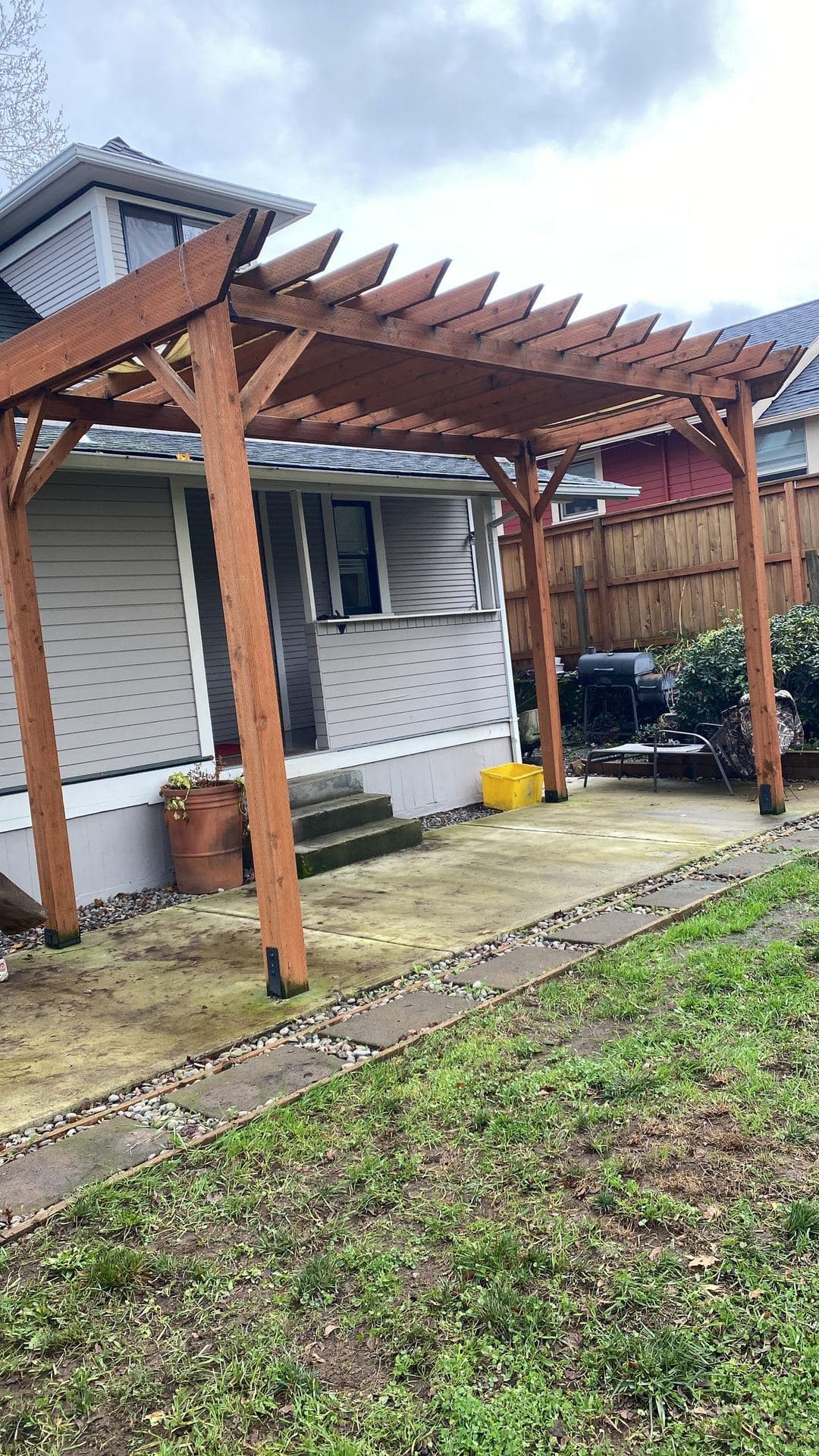 Finished stained cedar pergola over a concrete patio