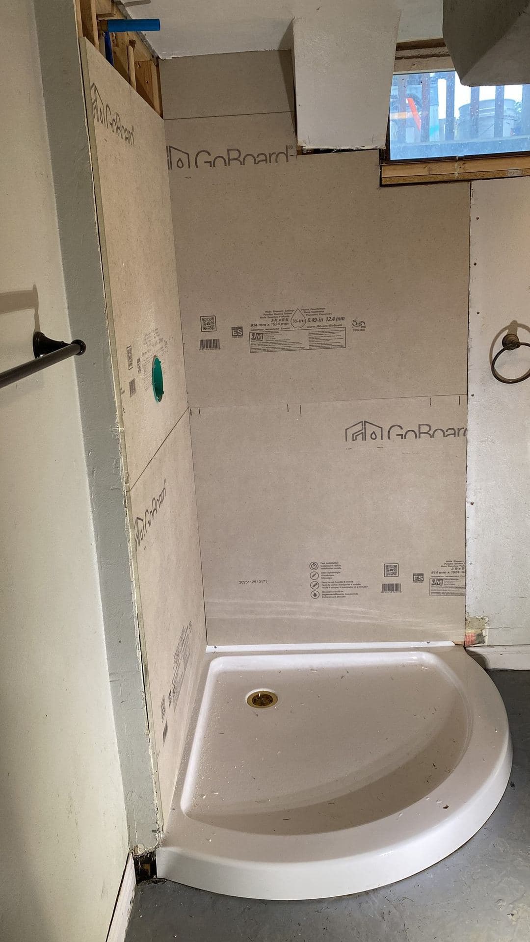 Shower base installed against waterproof backer board during a bathroom remodel