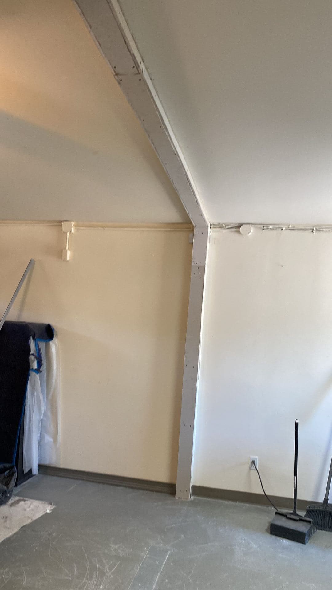 Unfinished drywall corner and beam with visible screws before taping