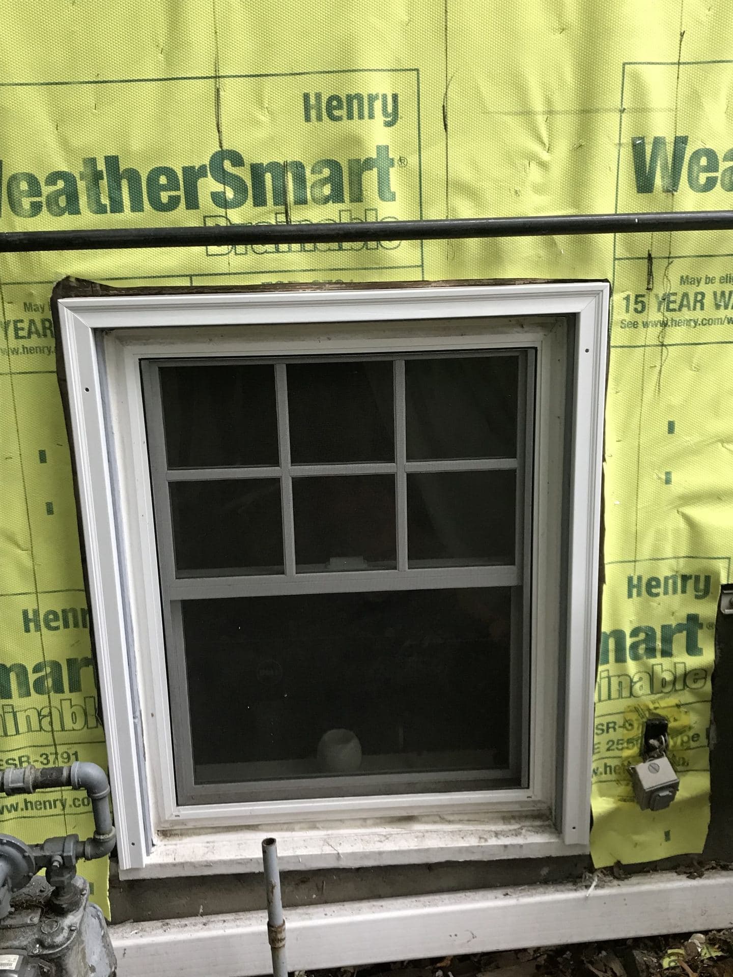 New vinyl window set in a housewrap-wrapped rough opening