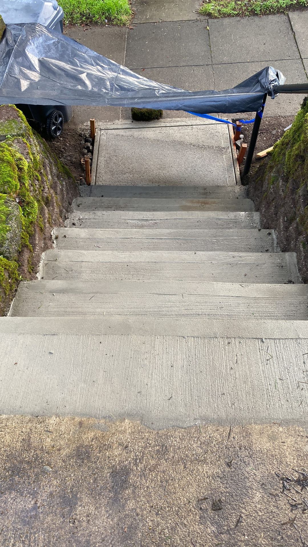 New broom-finished concrete steps and landing between mossy rock walls